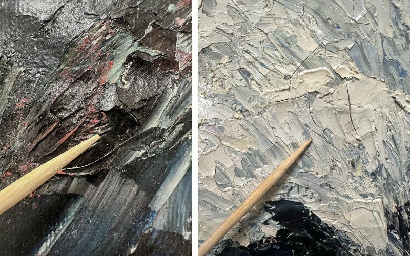 Close-up photographs of a textured painting, split into two sections. The left side showcases a dark, heavily textured surface with black, deep red, and blue tones, with thick paint layers creating a rugged effect. A wooden stick points to an area with cracked and peeling paint. The right side features a lighter, more muted palette of beige, gray, and blue, with similarly thick and expressive brushstrokes. A wooden stick also points to a section of the painting, emphasizing its texture and cracks.