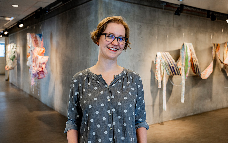 A woman in front of her artworks in a gallery