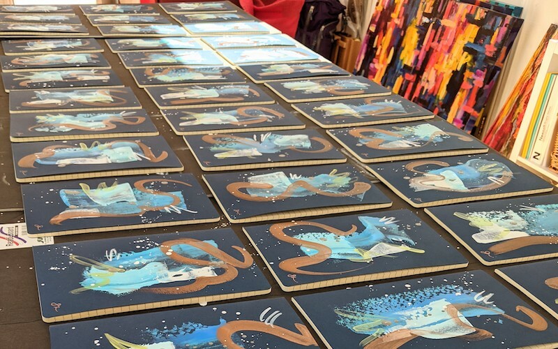 A long table displaying a range of similar artworks for a commission. 