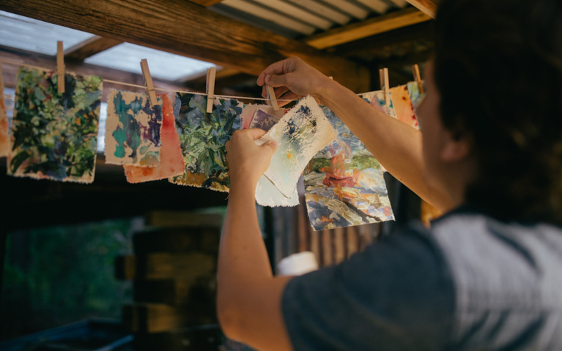 A painter hanging up paintings