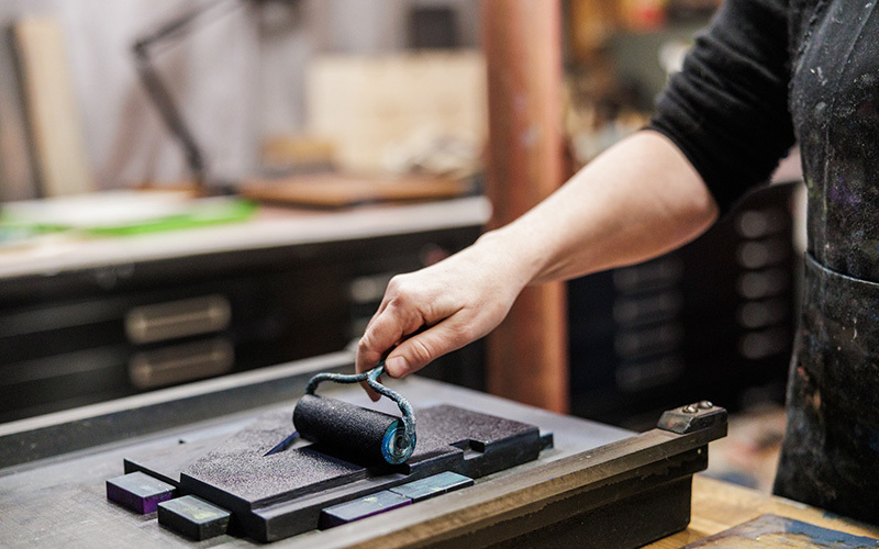 A woman applying ink to a roller to create artworks