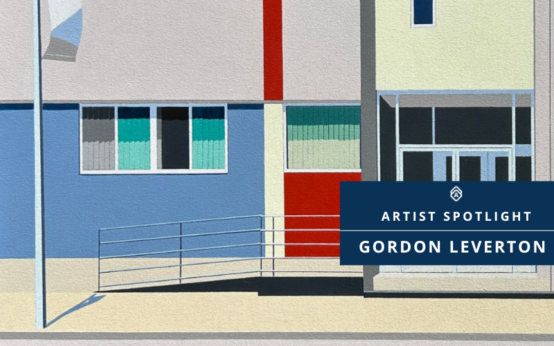A geometric painting by Gordon Leverton titled Accordance (24 x 36 x 1.5 in), depicting a modern building façade with blue, red, and yellow panels, rectangular windows, and a ramp in front. A flagpole casts a long shadow on the pavement. Overlaid text in a dark blue box reads: “ARTIST SPOTLIGHT GORDON LEVERTON.”